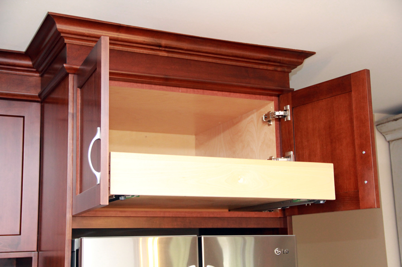 Pull-out shelf optimizes storage above fridge.