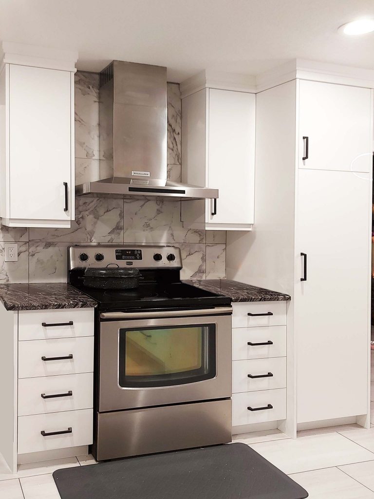 Kitchen stove wall in gloss white with plain slab cabinet doors and drawers