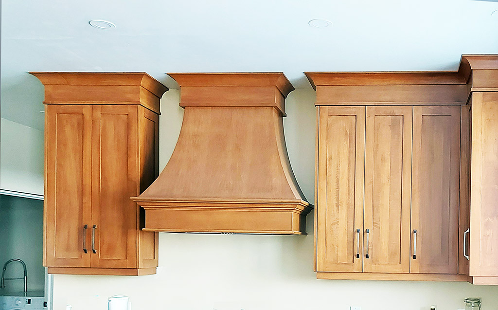 Photo of upper cabinets in medium maple with large wood fan hood